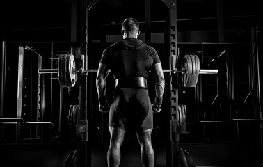 Professional athlete stands in front of the bars with a barbell and is about to crouch with her.