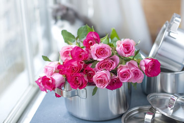 A bouquet of fresh pink roses, in a saucepan made of steel, on a gray stone background. Near the window . Home cat. Free place to write text or postcard.