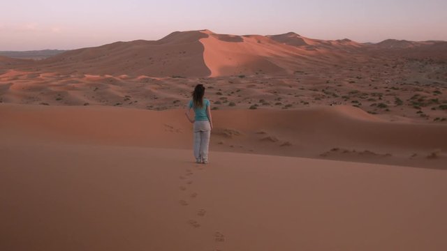Femme contemplant le coucher du soleil sur les dunes g&eacute;antes de Merzouga, dans le Sahara marocain