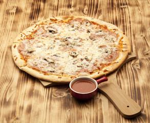 Pizza Capricciosa on wooden board served with ketchup
