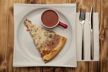 a piece of pizza capricciosa on a plate served with ketchup