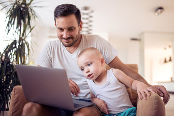 Father and son looking at laptop and smiling.
