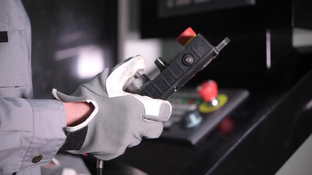 Production Line Operator with Wired Remote For CNC Machine. Closeup Video.