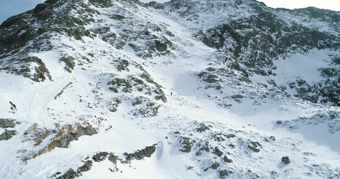 Forward aerial over winter snowy mountain with mountaineering skier people walking up climbing.snow covered mountains top and ice glacier.Winter wild nature outdoor establisher.4k drone flight