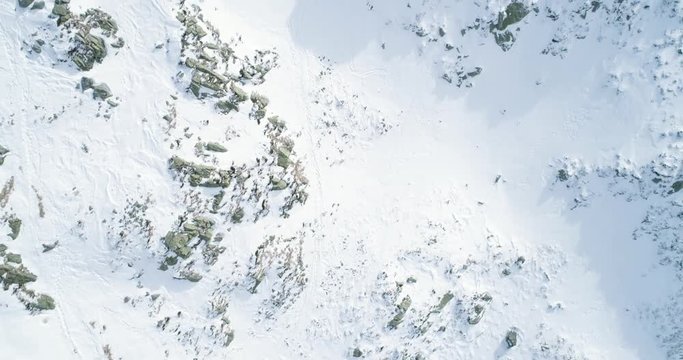 Overhead aerial top view over winter snowy mountain with mountaineering skier people walking up climbing.snow covered mountains ice glacier.Winter wild nature outdoor.4k drone straight-down flight