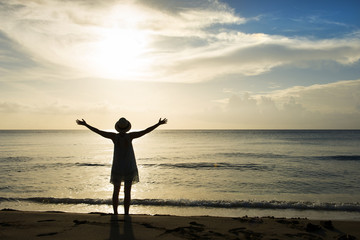 Fototapeta premium Silhouette of Woman with Arms Outstretched on the Beach