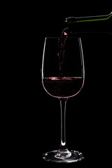 Large glass of red wine is pouring wine from a bottle of red .