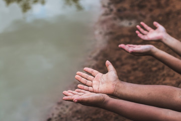 The hands of children who need water on an arid soil.