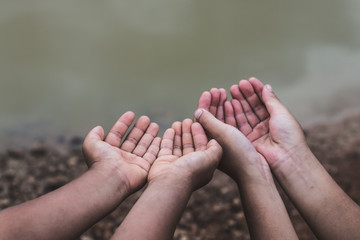 The hands of children who need water on an arid soil.