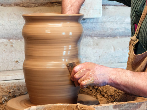 Hands of a Potter make a big vase on a pottery wheel.