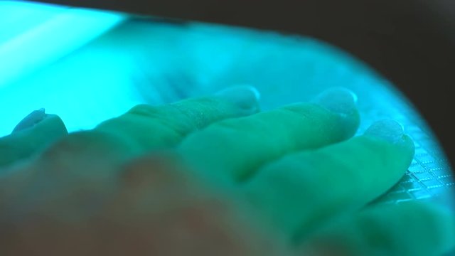 Hand under the lamp for polymerization of nails after extensions at beautician