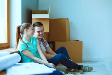 Couple moving in house sitting on the floor. Couple