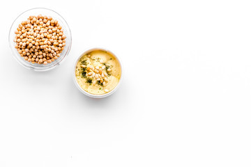Middle Eastern cuisine. Bowls with hummus and chickpeas on white background top view copy space