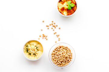 Middle Eastern cuisine. Bowls with hummus and chickpeas on white background top view copy space