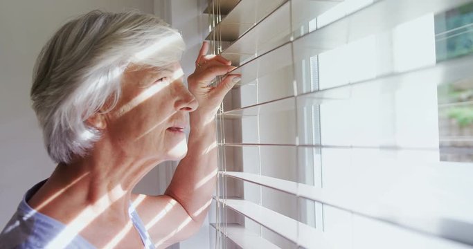 Senior woman looking through the window 