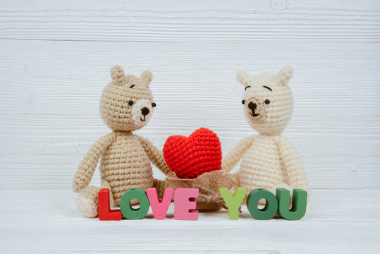 Sweet couple teddy bear doll in love with Love text and red knitting heart on white wooden background and copy space for add text and picture, love and valentine day concept.