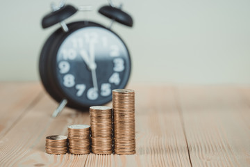 Steps of coins stack with vintage alarm clock on wooden working table with copy space for text, financial and business planning concept. vintage tone.