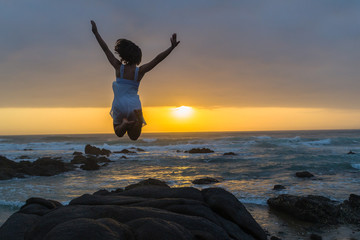 Young Girl Ballet Dancer on beach rocky coastline pose leap silhouetted dawn sunrise
