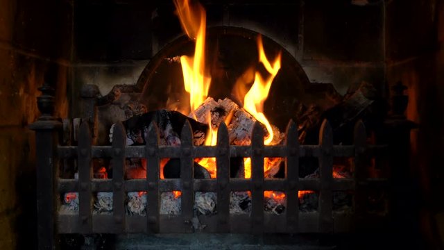 Close up 4K video clip of logs burning in a traditional fireplace.