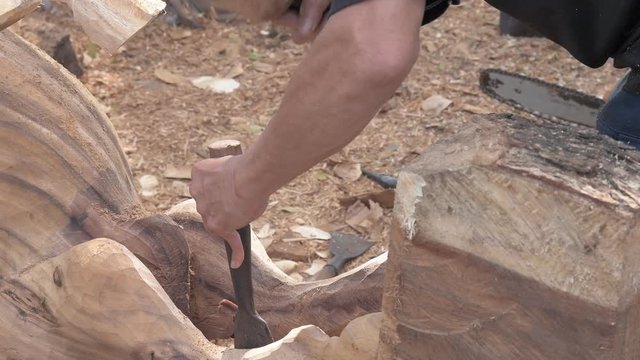 Hands of craftsman carve with a gouge in the hands on the workbench in carpentry