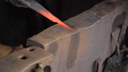 Blacksmith working metal with hammer on the anvil in the forge. hammer forging hot iron at anvil. Blacksmiths make machete. Hands of the smith by the work. Philippines.