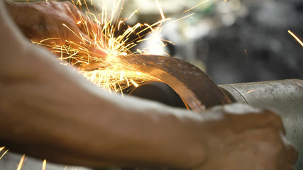 Sharpening the machete on sharpening machine in the smithy. Knife sharpener and hand with blade. Worker sharpening machete with grindstone abrasive disc cutter machine.