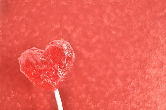 A red heart shape lollipop isolated against a red background