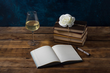 Glass with Wine, An Open Book and Pen, Books Are Knitted by a Juggle Rope, White Rose Bud on a Wooden Table