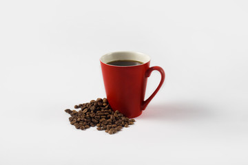 Red cup with Coffee and Grains Coffee scattered around. Taken at an angle