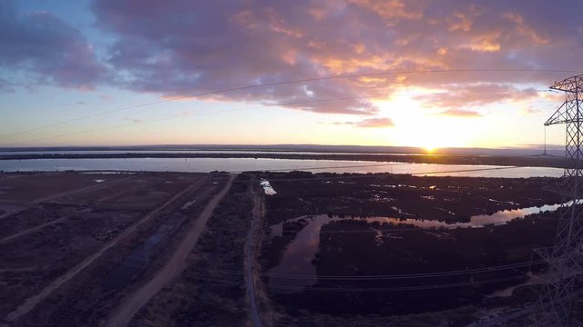 Drone footage of remote industrial area near power station and high-voltage towers at sunrise. Taken at Outer Harbor, Port Adelaide, South Australia.