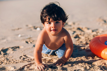 portrait of a beautiful baby boy playing on the shoreline
