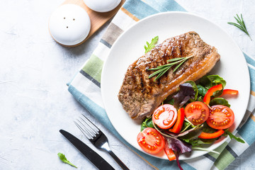 Grilled beef striploin steak with fresh salad. Top view.