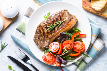 Grilled beef striploin steak with fresh salad. Top view.
