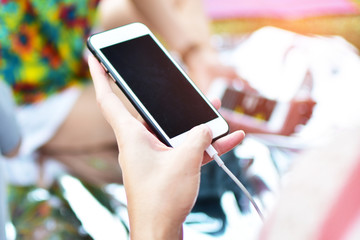 hand holding and touch screen smart phone at the park with blur background. subject is blurred.