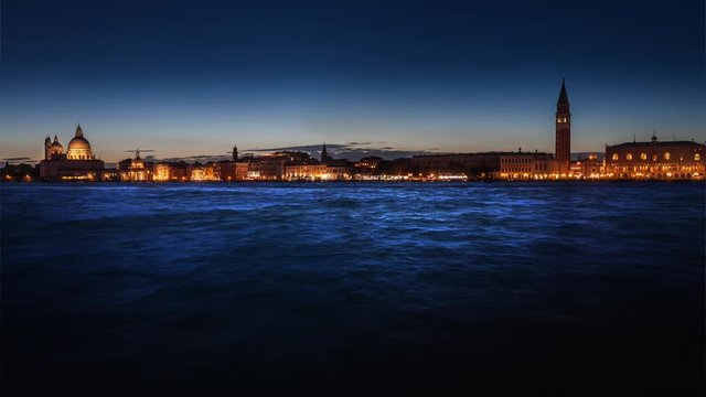 Night panoramic view of illuminated Venice and waving sea. Looping cinemagraph.