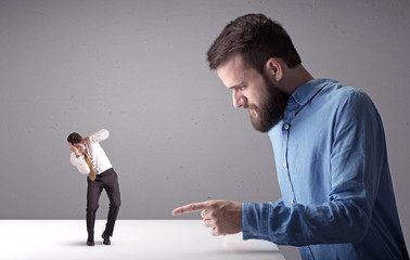 Young businessman fighting with miniature businessman