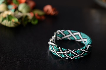 Green bead crochet bracelet with celtic print on a dark background close up