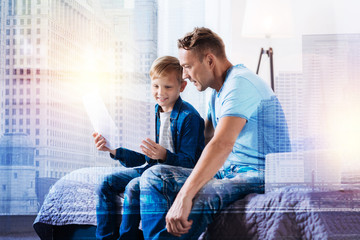 Be attentive. Cheerful blonde boy keeping smile on his face and holding papers while choosing the...