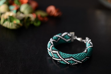 Green bead crochet bracelet with celtic print on a dark background close up