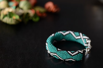 Green bead crochet bracelet with celtic print on a dark background close up