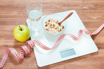 Healthy diet, fitness and weight loss concept. Weights, roulette, apple, oatmeal, a glass of water, an open notebook and a pencil on the table.