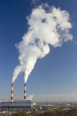 Smoke from industrial chimneys against the blue sky. Pollution.