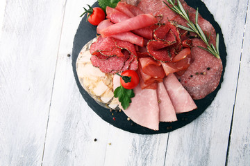 Food tray with delicious salami, pieces of sliced ham, sausage, tomatoes, salad and vegetable - Meat platter with selection