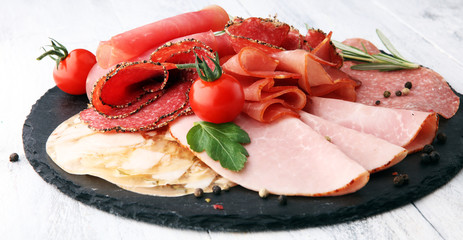 Food tray with delicious salami, pieces of sliced ham, sausage, tomatoes, salad and vegetable - Meat platter with selection