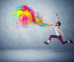 Hipster guy shouting colorful paint on wall