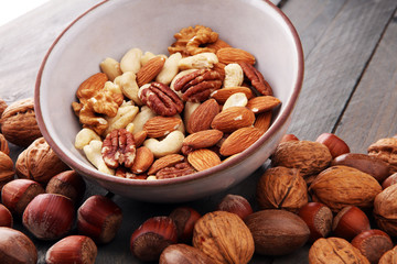bowl with mixed nuts on wooden background. Healthy food and snack. Walnut, pecan, almonds, hazelnuts and cashews.