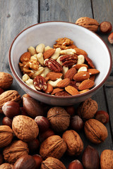 bowl with mixed nuts on wooden background. Healthy food and snack. Walnut, pecan, almonds, hazelnuts and cashews.