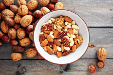 bowl with mixed nuts on wooden background. Healthy food and snack. Walnut, pecan, almonds,...