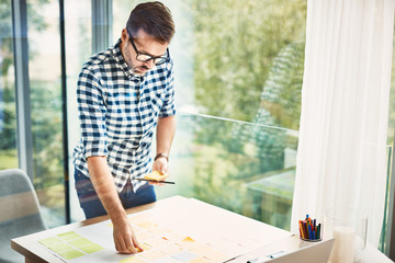 Handsome designer working with notes from modern office