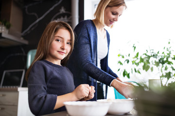 Fototapeta premium A small girl with her mother cooking at home.